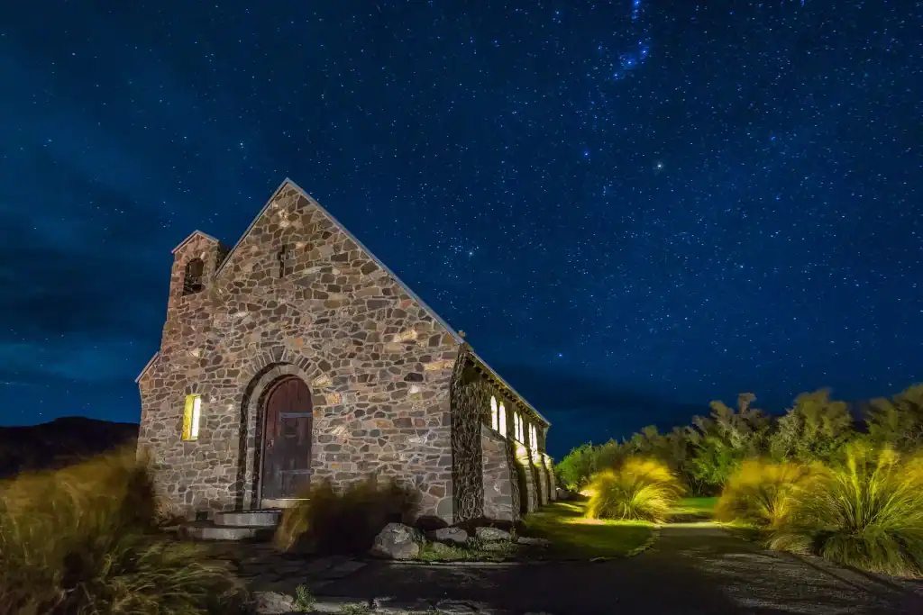 Starlit night sky above a rustic stone church in a peaceful rural setting, ideal for night sky gazing and spiritual retreats.