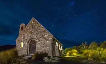 Starlit night sky above a rustic stone church in a peaceful rural setting, ideal for night sky gazing and spiritual retreats.