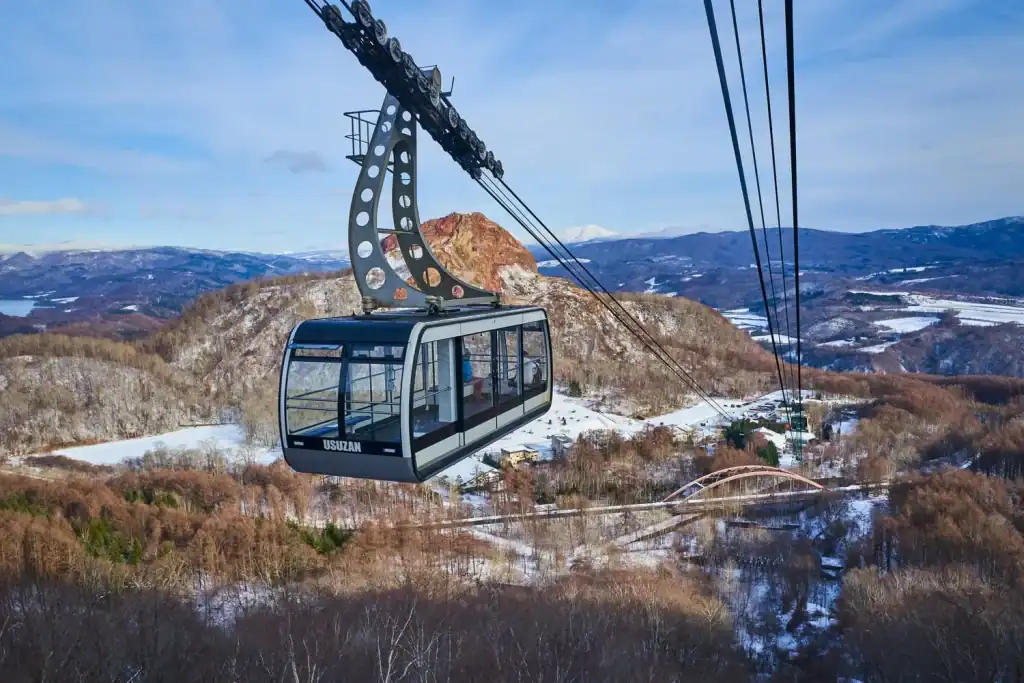Cable car ride over snow-covered mountains in Japan, offering breathtaking views and a unique travel experience amidst nature.