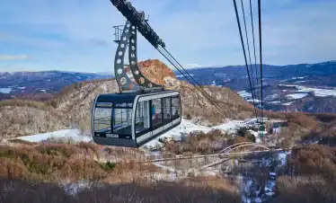 Cable car ride over snow-covered mountains in Japan, offering breathtaking views and a unique travel experience amidst nature.
