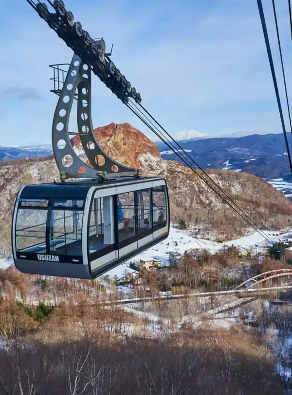 Cable car ride over snow-covered mountains in Japan, offering breathtaking views and a unique travel experience amidst nature.